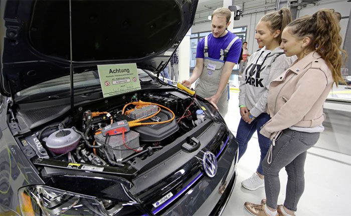 Kraftfahrzeug-Mechatroniker für System- und Hochvolttechnik zeigt Gästen an einem e-Golf, worauf bei Arbeiten an Elektro-Fahrzeugen zu achten ist.