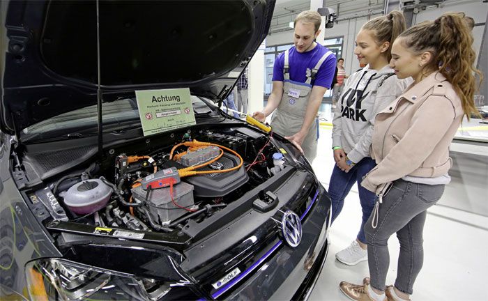 Kraftfahrzeug-Mechatroniker fr System- und Hochvolttechnik zeigt Gsten an einem e-Golf, worauf bei Arbeiten an Elektro-Fahrzeugen zu achten ist.
